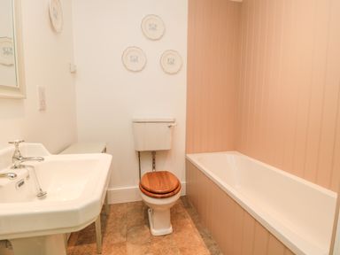 A bathroom with a sink toilet with wooden seat and a bathtub at The Garden Cottage in West Woodburn