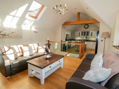 A living room with two brown sofas a wooden coffee table and a kitchen in the background at Bwthyn Carregwen in Dwygyfylchi
