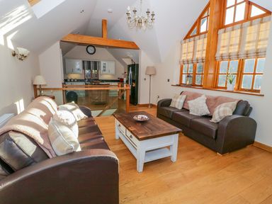 A living room with two brown sofas a wooden coffee table and large windows at Bwthyn Carregwen in Dwygyfylchi