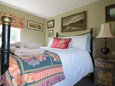 A bedroom with a bed covered with white bedding and colorful carpet at Crows Cabin in Gloucester