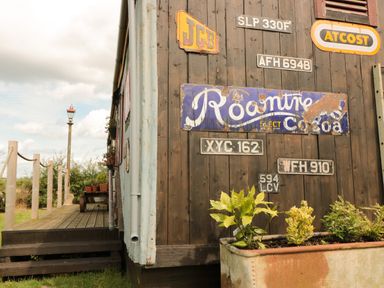 Exterior of a building with vintage signs and plants in a planter at Crows Cabin in Gloucester