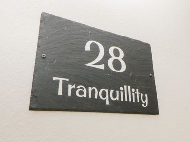 Black house number sign with white text 28 Tranquillity on a light wall at Tranquillity Rosecraddoc Lodge near Liskeard