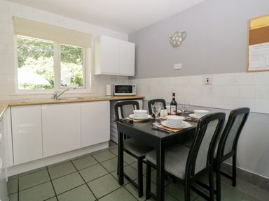 A kitchen with a dining table set for four near a window in Tranquillity Rosecraddoc Lodge near Liskeard