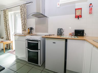 A kitchen with an oven stovetop a kettle a toaster and a small refrigerator at Tranquillity Rosecraddoc Lodge near Liskeard