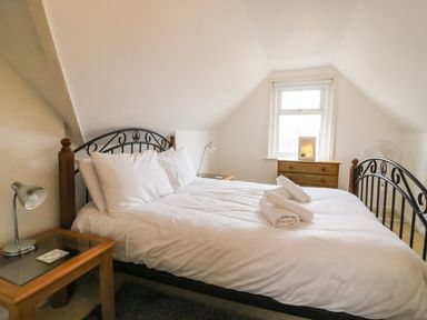 A bedroom with a double bed white linens bedside tables lamps and a wooden chest of drawers at Brewers House in Weymouth