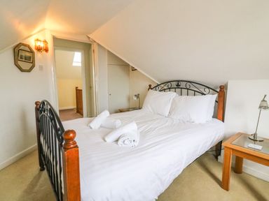 A bedroom with a double bed with white linens and rolled towels a bedside table with a lamp and a wall sconce at Brewers House in Weymouth