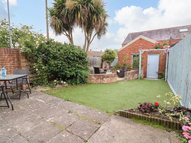 A garden with patio furniture a lawn and a brick seating area at Brewers House in Weymouth