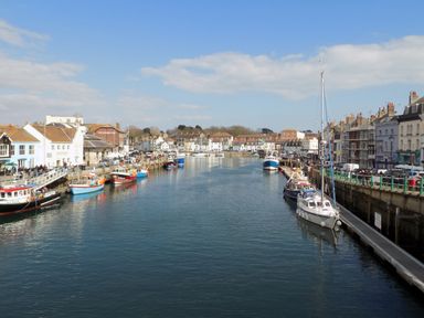 A harbor with boats docked along waterfront buildings and a calm body of water at Brewers House in Weymouth
