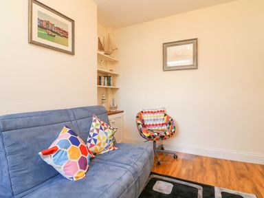 A small sitting room with a blue sofa with colorful cushions and a multi colored chair at Brewers House in Weymouth