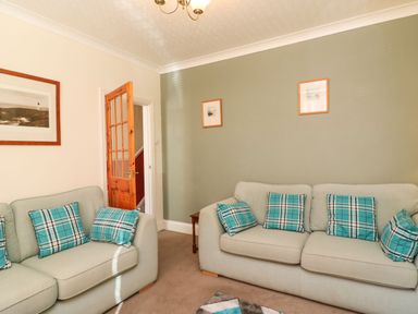 A living room with two sofas with blue plaid cushions and framed pictures on the walls at Brewers House in Weymouth