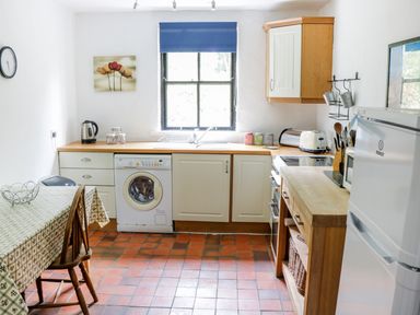 A kitchen with a table and chairs a washing machine a sink a stove a refrigerator and kitchen cabinets at An Teach Ban in Rossaveel County Galway