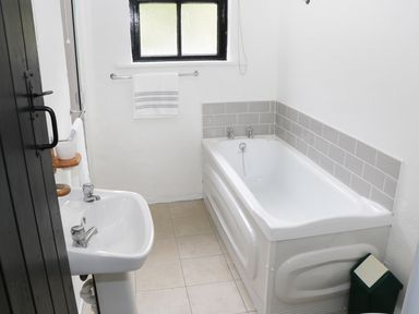 A bathroom with a bathtub sink towel and window at An Teach Ban in Rossaveel County Galway