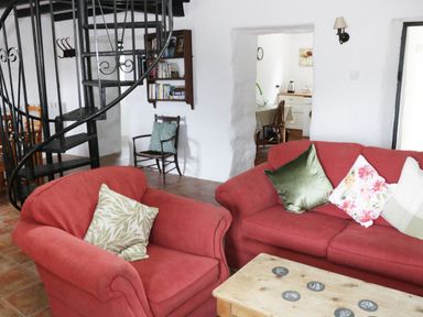 A living room with red sofas a wooden coffee table and a spiral staircase at An Teach Ban Rossaveel County Galway