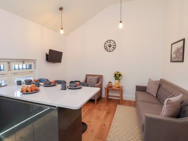 A living room with a sofa, table, and television at Evening Star @ Engine Shed Whitby