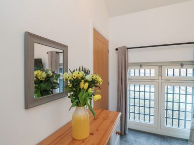 An entrance hall with a mirror and flowers on a table at Evening Star @ Engine Shed in Whitby