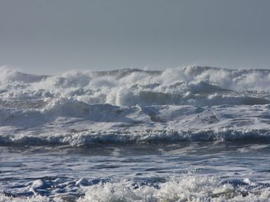 Ocean waves crashing with foam and spray under a grey sky