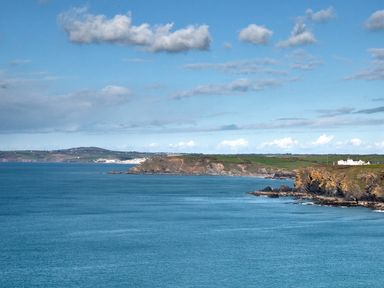 A coastal landscape with cliffs and buildings in the distance at Kober House in Mullion