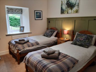 A bedroom with two single beds and a window at Hemmel Cottage in Chatton
