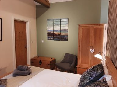 A bedroom with a bed and armchair at Hemmel Cottage in Chatton