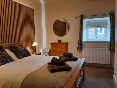 A bedroom with a bed and chest of drawers at Hemmel Cottage in Chatton