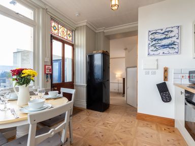 A kitchen and dining area with a round table set with dishes and flowers and a black refrigerator at Bayview Terrace in Lynton