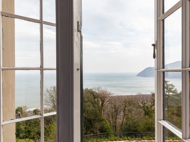 A view of the sea and hills through open glass windows at Bayview Terrace in Lynton