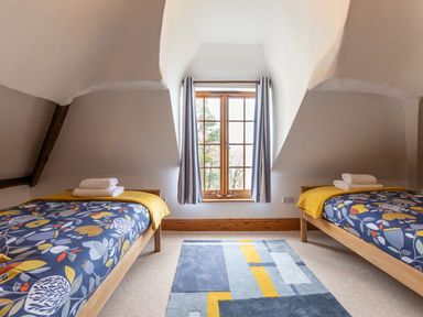 A bedroom with two single beds a window with curtains and a rug on the floor at Bayview Terrace in Lynton