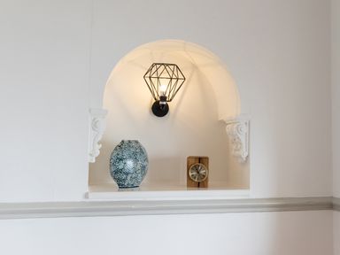 A wall niche with a decorative vase a wooden clock and a wall light at Bayview Terrace in Lynton