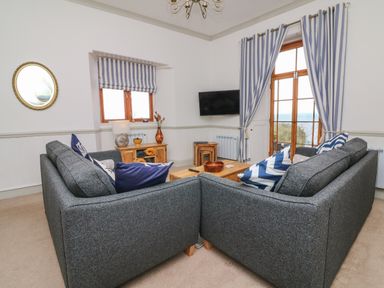 A living room with two gray sofas and blue striped curtains at Bayview Terrace in Lynton