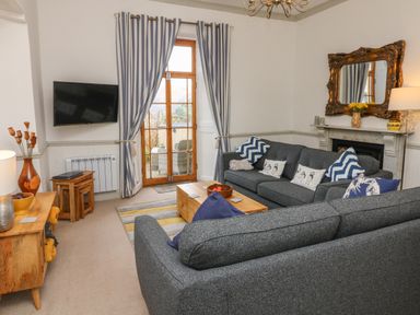 A living room with striped curtains wooden coffee table and grey sofas at Bayview Terrace in Lynton