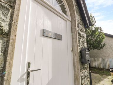A white door with a metal handle and a sign that reads Capel Horeb stone wall and a mailbox outside at Horeb Chapel House in Tanygrisiau