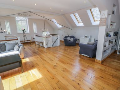 A sitting area with sofas armchairs and skylights in a room with wooden floors at Horeb Chapel House in Tanygrisiau
