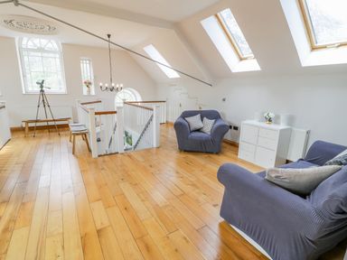 An upper floor seating area with two armchairs a small cabinet telescope and skylight windows at Horeb Chapel House Tanygrisiau