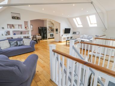 An open living space with couches stairs and a kitchen in the background at Horeb Chapel House in Tanygrisiau