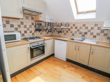 A kitchen with wooden floors cream cabinets a gas stove oven microwave dishwasher and a skylight window at Horeb Chapel House in Tanygrisiau