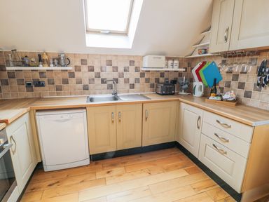 A kitchen with wooden floor beige cabinets a tiled backsplash and a skylight window at Horeb Chapel House in Tanygrisiau