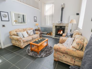 A living room with two patterned sofas a wooden coffee table a rug a stone fireplace and lamps at Horeb Chapel House in Tanygrisiau