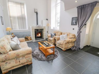 A living room with a fireplace sofas coffee table and a curtain at Horeb Chapel House in Tanygrisiau