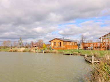 A wooden lodge with a deck by a lake with wooden piers at Lake View Lodge in Marston near Barkston