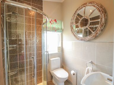 A bathroom with a corner shower enclosure a toilet a sink and a round mirror at Lake View Lodge Marston near Barkston