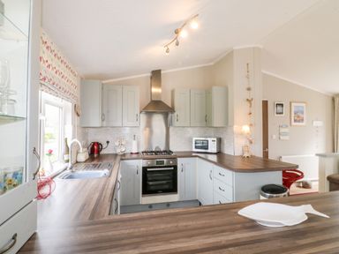A kitchen with wooden countertops, a gas stove, microwave, sink, and cabinets at Lake View Lodge in Marston near Barkston