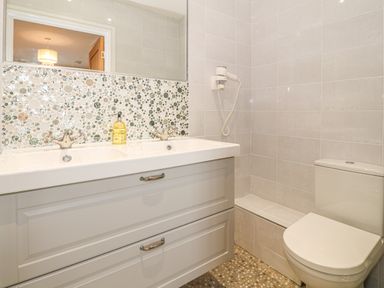 A bathroom with a double sink vanity a wall-mounted hairdryer and a toilet at Holly Cottage in Criccieth