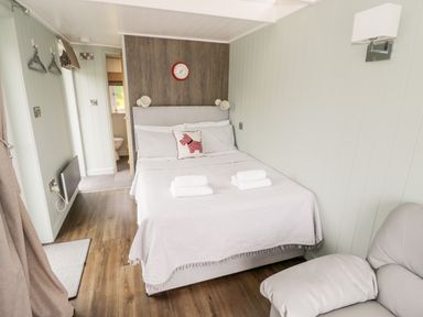 A bedroom with a bed with white linens and towels a chair and a bathroom visible at Hydrangea in Bretforton