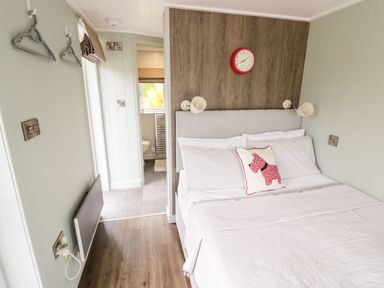 A bedroom with a double bed and a pillow with a dog design next to a bathroom at Hydrangea in Bretforton
