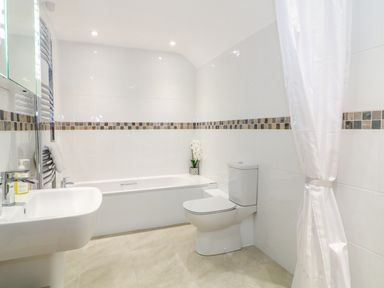 A bathroom with a sink a bathtub a toilet and a shower curtain at Shippon Barn in Yeovil