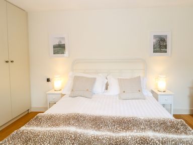 A bedroom with a double bed two bedside tables with lamps and framed pictures on the wall at Shippon Barn in Yeovil