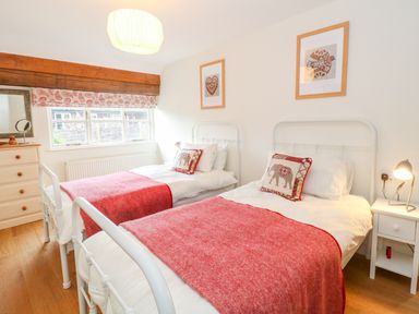 A bedroom with two single beds with red blankets and elephant cushions at Shippon Barn in Yeovil