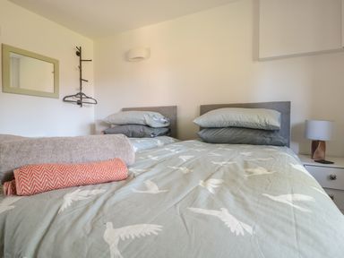 A bedroom with two single beds joined together with folded towels on the bed at Black Cat Bach in Gilwern