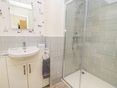 A bathroom with a sink cabinet mirror and a glass shower enclosure at Lambs Lodge in Bamburgh