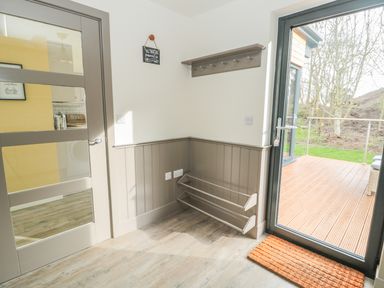 A corner of a room with a door leading outside and a wall-mounted coat rack at Lambs Lodge in Bamburgh